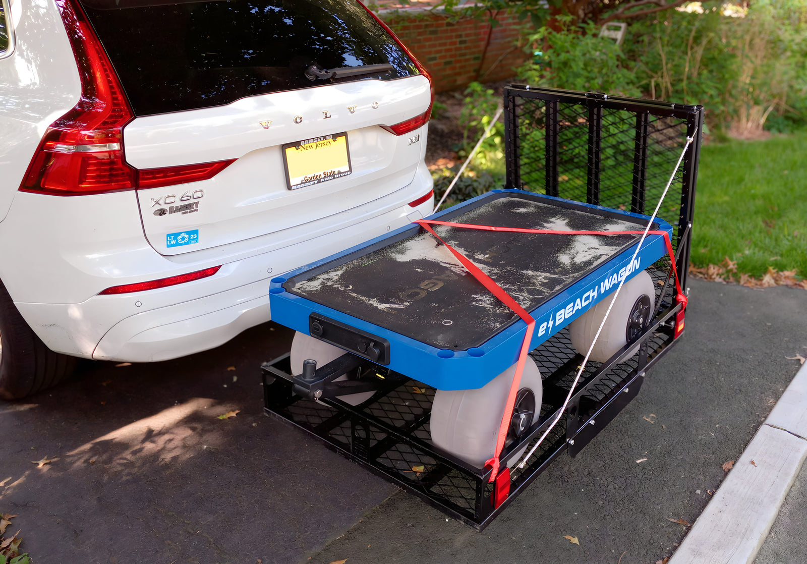 SUV with a hitch carrier attached, loaded with an e-Beach wagon, on a driveway.